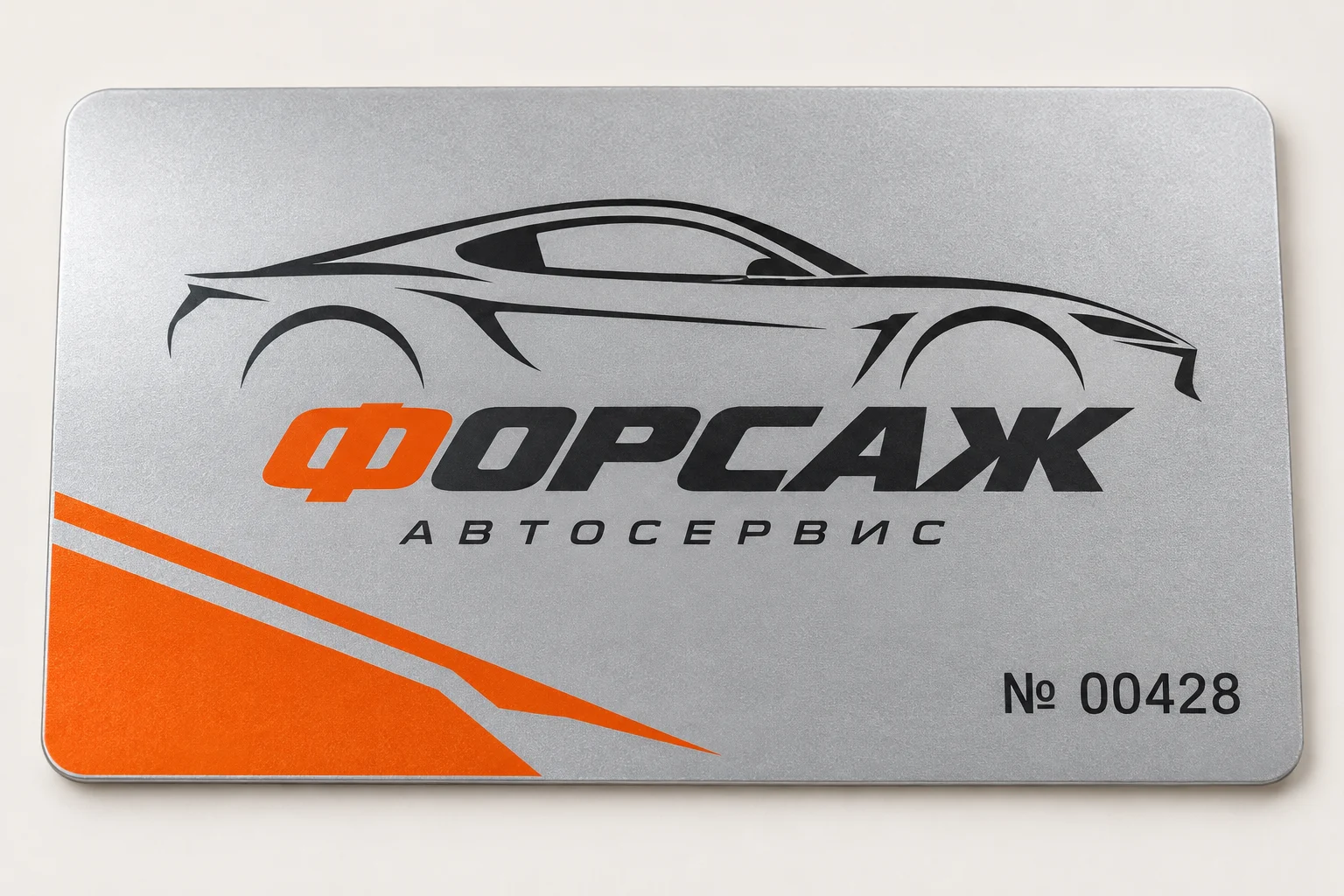 Серебряный пластик крупным планом: карта автосервиса ФОРСАЖ с чёрным автомобилем, оранжевым акцентом и номером 00428